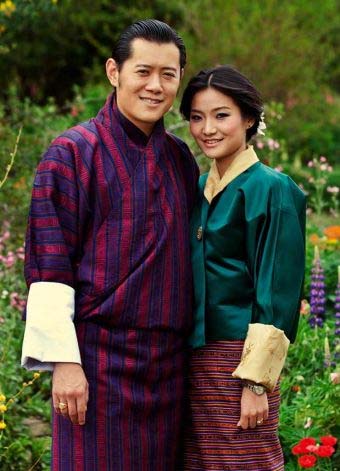 De koning en koningin van Bhutan poseren in de tuin in traditionele kleding
