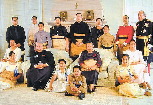 De koninklijke familie van Tonga poserend in traditionele kledij, sommige mensen staan, sommige zitten op de grond.